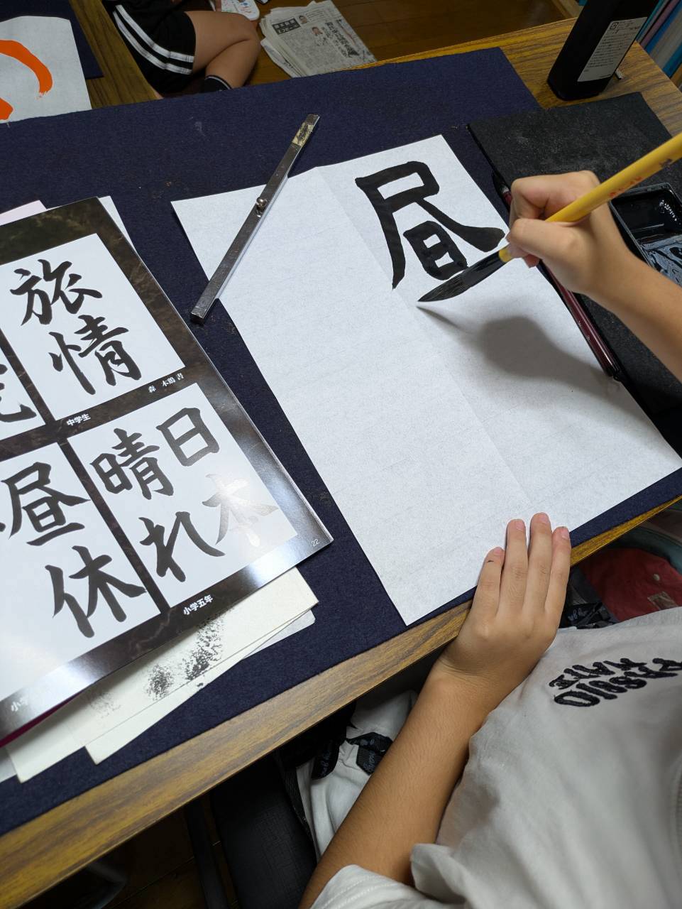 千詠書道 志木市教室でお手本を見ながら「昼休」の「昼」を毛筆で書く生徒さん