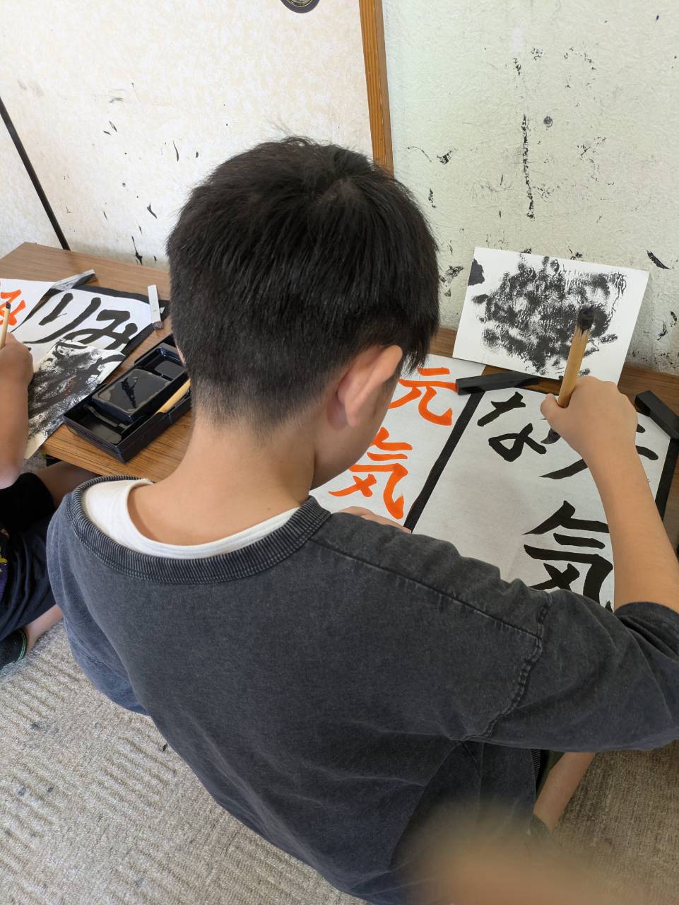 千詠書道 川越教室で朱色のお手本を見ながら「気」の字を書く男の子